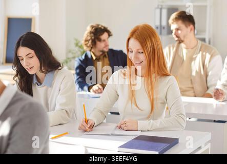 Students in bright classroom taking notes during lesson, group study and learning Stock Photo