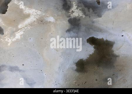Water Stains On Concrete Surface. Abstract view of damp marks and moisture patterns on gray cement floor, suitable for industrial textures or architec Stock Photo