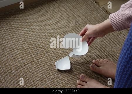 Person picks up broken plate on the floor Stock Photo