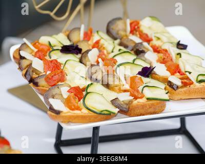 Assorted gourmet vegetable appetizers with tartines and zucchini rolls served as elegant finger food on a catering buffet table. Stock Photo