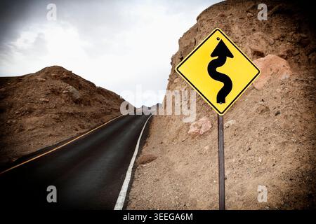 Road and Road Sign showing winding road ahead, Death Valley National Park, Death Valley, California, USA Stock Photo