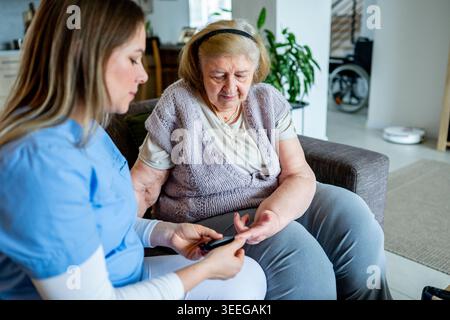 Diabetologist nurse testing blood sample on blood sugar meter. Stock Photo