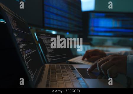 Developers coding a new application project at a multi screen workstation with laptop and digital devices, showing software development workflow, prog Stock Photo