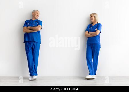Male and female doctors standing on white background looking at each other Stock Photo
