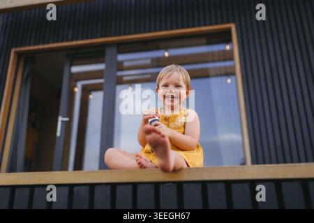 Small child playing outdoors, weekend away in container house in countryside. Stock Photo