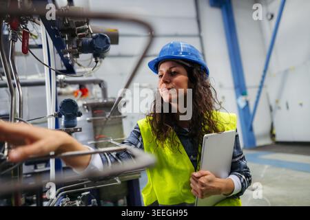 Female worker checking industrial control systems in production environment. Stock Photo