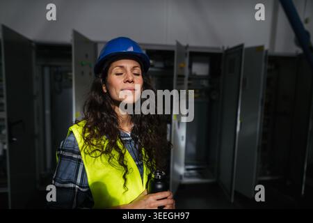 Female worker checking industrial control systems in production environment. Stock Photo