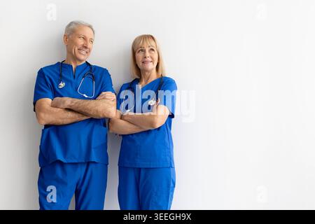 Senior healthcare team in blue medical scrubs posing with crossed arms Stock Photo