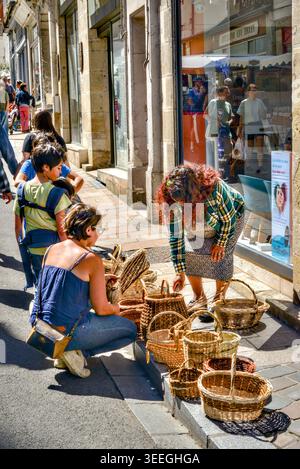Gypsy woman selling her woven baskets from the pavement - Loches, Indre-et-Loire (37), France. Stock Photo