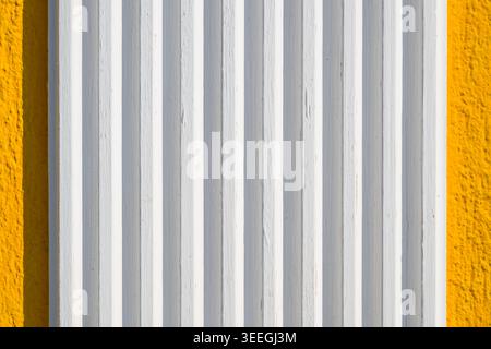 Texture of smooth white plastered panels with subtle vertical grooves and faint surface imperfections, sharply contrasted against a bold textured yell Stock Photo
