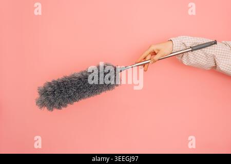 Hand with gray duster on pink background in close up Stock Photo