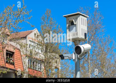 Traffic surveillance and speed enforcement cameras mounted on a pole overlooking residential street, capturing vehicle and pedestrian movement for pub Stock Photo
