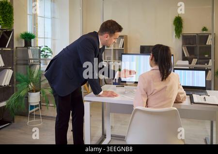 Business team analyzing financial spreadsheets on computer screens in office Stock Photo