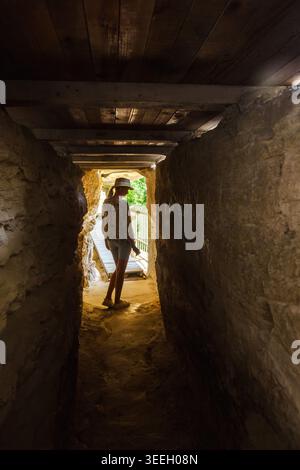 Young woman exploring narrow cave corridor inside Aladzha Monastery Bulgaria Stock Photo
