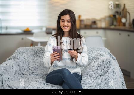 Woman shopping online using smartphone and credit card Stock Photo