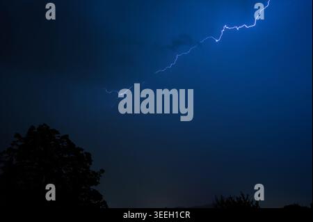 Dramatic lightning bolt illuminating a dark night sky during a ...