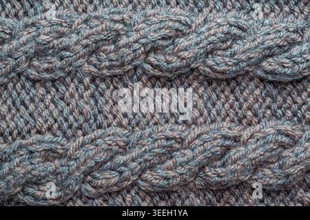 Detailed macro shot showcasing the intricate patterns and textures of a woolen cable knit textile, highlighting the yarn's natural fibers and weave Stock Photo