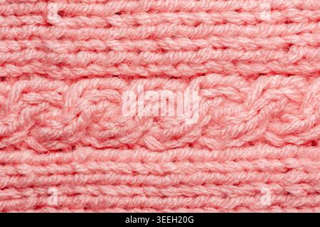 Detailed texture of soft pink yarn woven into a classic cable knit pattern, showcasing intricate stitches and cozy warmth Stock Photo