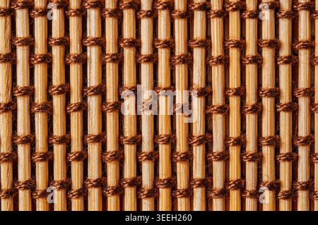 Detailed view of a natural bamboo mat, showcasing the texture of the reeds and the intricate weaving pattern of the brown twine Stock Photo