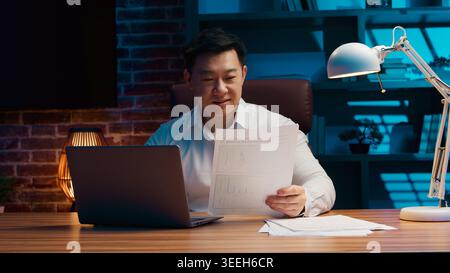 Asian business man with laptop smiling working with internet and documents papers Korean businessman with computer device work paperwork online job Stock Photo