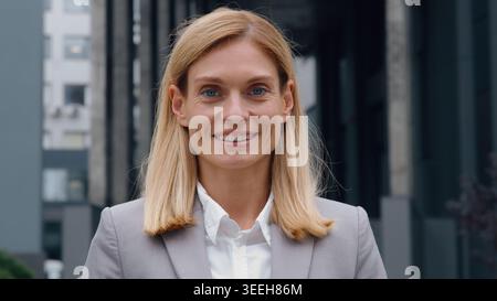 Close-up Caucasian adult business woman smiling in city near company building happy cheerful positive successful businesswoman outdoor smile looking Stock Photo