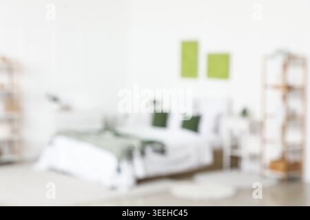 Blurred view of stylish bedroom with cozy bed and beautiful paintings Stock Photo