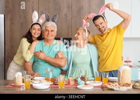Happy family with bunny ears at Easter dinner in kitchen Stock Photo