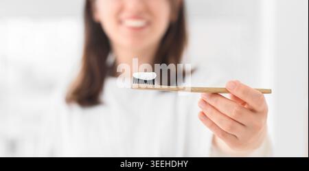 Hand of woman with applied paste on bamboo tooth brush in bathroom, closeup Stock Photo