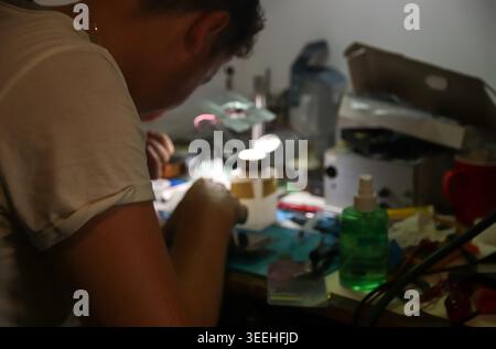 Technician repairing a smartphone under a microscope in a specialized workshop. Close-up of a professional worker soldering electronic components on a Stock Photo