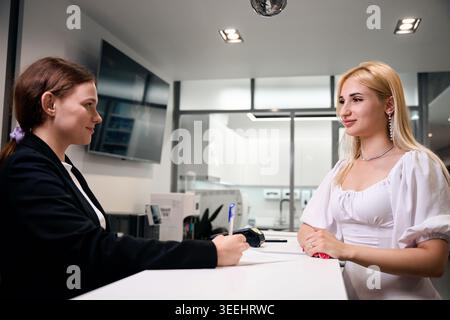 Two women collaborating at reception desk in modern office Stock Photo