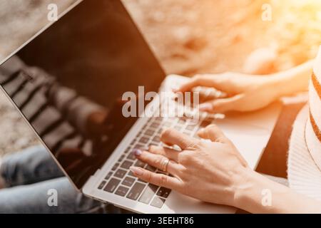 Typing laptop freelancer woman working on a silver computer outdoors representing a remote digital nomad lifestyle Stock Photo