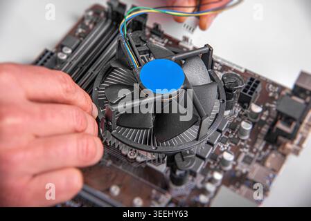 A person's hands installing a cooling fan onto a CPU socket. Stock Photo