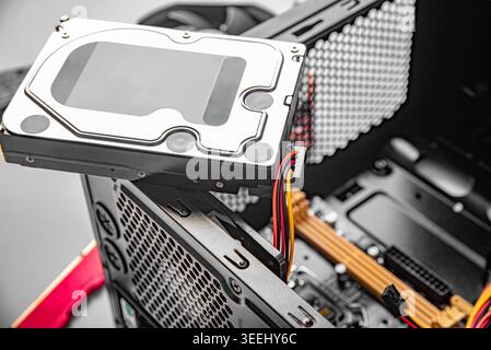 A 3.5-inch internal hard drive being installed or removed from a black desktop computer tower case Stock Photo