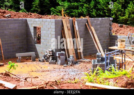Workers are constructing brick wall at construction site with tools materials on ground around it. Stock Photo