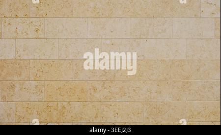 Light yellow travertine wall made of large rectangular tiles. Background and texture. Full frame. Stock Photo