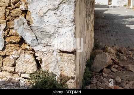 Stone wall of a house with large cracks from an earthquake. Damage to a stone wall with visible stones. Static problem in masonry Stock Photo