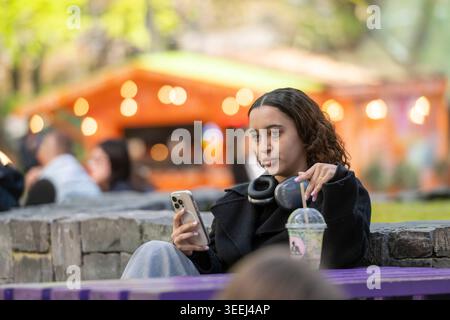Young woman using a smartphone while relaxing outdoors in Canary Wharf, London. Stock Photo