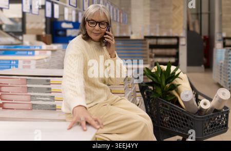 Woman shopping for home improvement materials, talking on phone in a building supply store Stock Photo