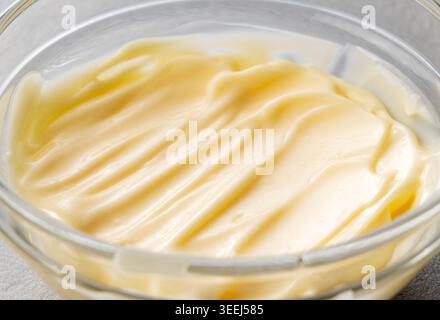 Creamy Mayonnaise with Texture Swirls in a Clear Glass Bowl on Grey Stone Background Stock Photo