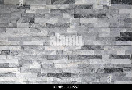 Stone cladding wall made of of white, gray and black stone bricks. Panels for exterior or interior. Full frame. Background and texture. Stock Photo