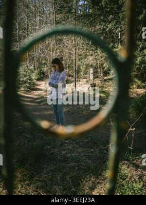 Woman framed through metal ring on forest trail near Treppoja Cascade, Estonia, in early spring Stock Photo