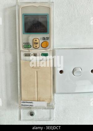 Device for controlling air conditioning is fixed on the wall. It shows settings for temperature and fan modes. Stock Photo