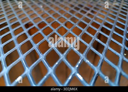 Metal grating creating a diamond pattern, forming a steel mesh with geometric detail. Industrial textured surface background Stock Photo
