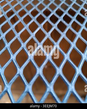 Blue metal mesh material forming a repetitive diamond pattern, showing an abstract background texture Stock Photo