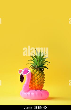 Summer tropical background with copy space for a text, pink flamingo with pineapple on yellow background Stock Photo