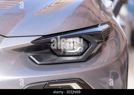Close up photo of modern LED car headlight on gray vehicle with stylish automotive design and glossy exterior details. Stock Photo