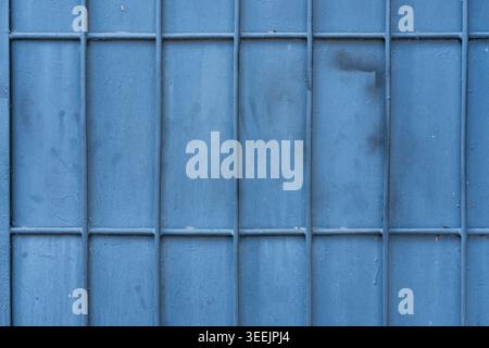 Detail of a blue-painted iron security gate with vertical and horizontal bars. Stock Photo