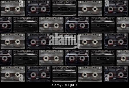 Pattern of vintage transparent and black audio cassettes arranged on a dark background. Stock Photo