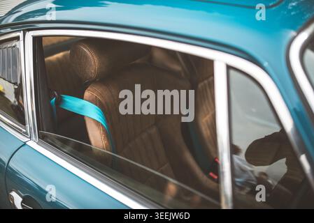 The vintage automobile's interior features a striking contrast between the leather seats and the vibrant seatbelt Stock Photo