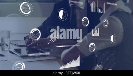 Reviewing two colleagues in suits examining tablet and documents at meeting table, with AR charts Stock Photo